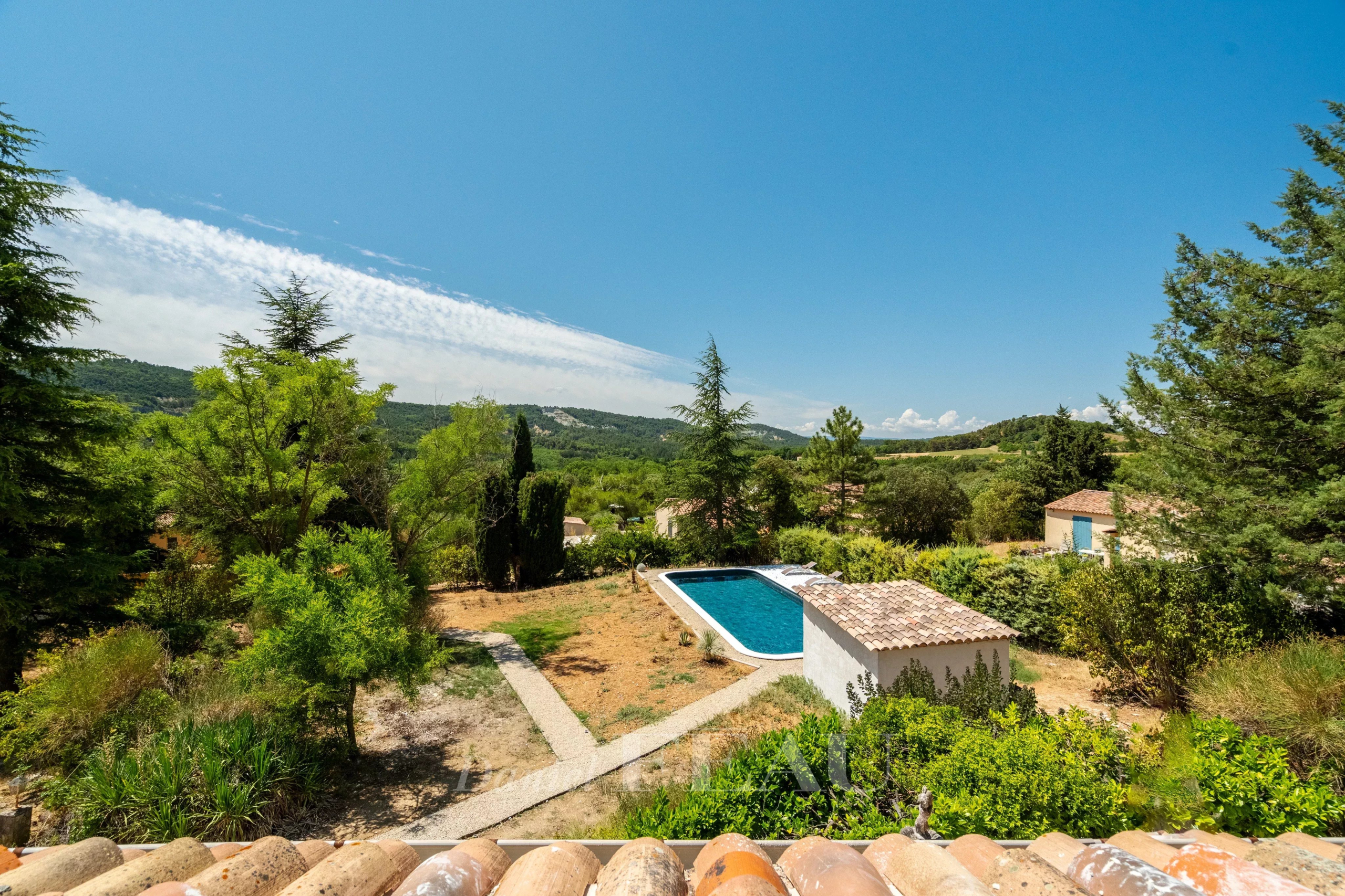 Vue panoramique sur une villa avec piscine et terrain paysager à Rustrel, entourée de verdure.
