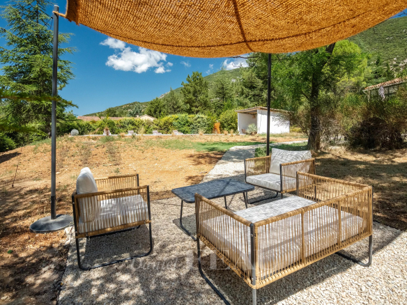 Terrasse extérieure avec mobilier en osier dans un jardin paysager à Rustrel.