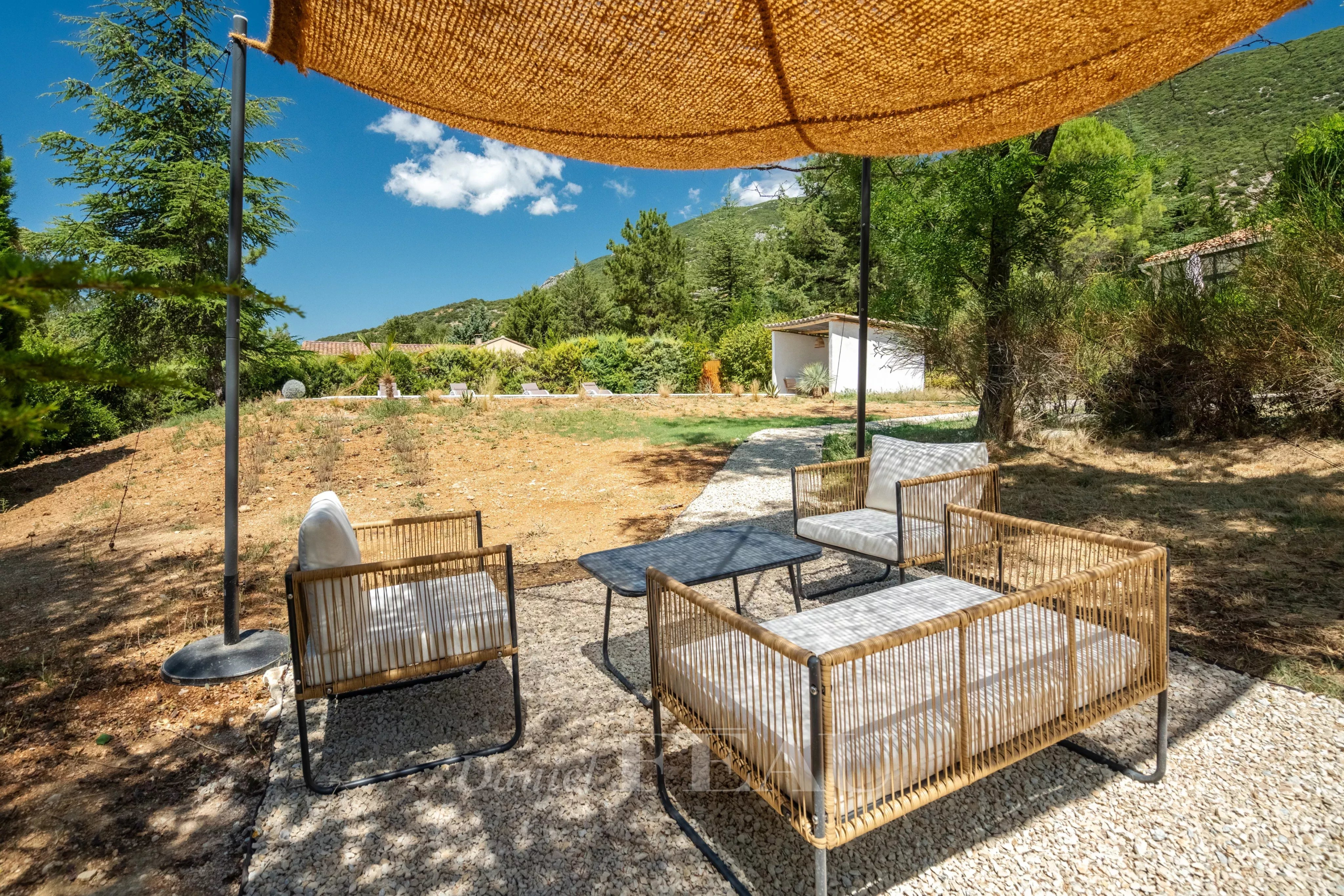 Terrasse extérieure avec mobilier en osier dans un jardin paysager à Rustrel.