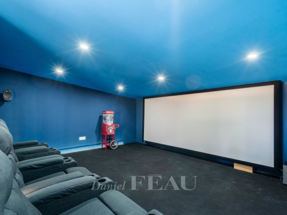 Salle de cinéma privée avec écran et fauteuils confortables.