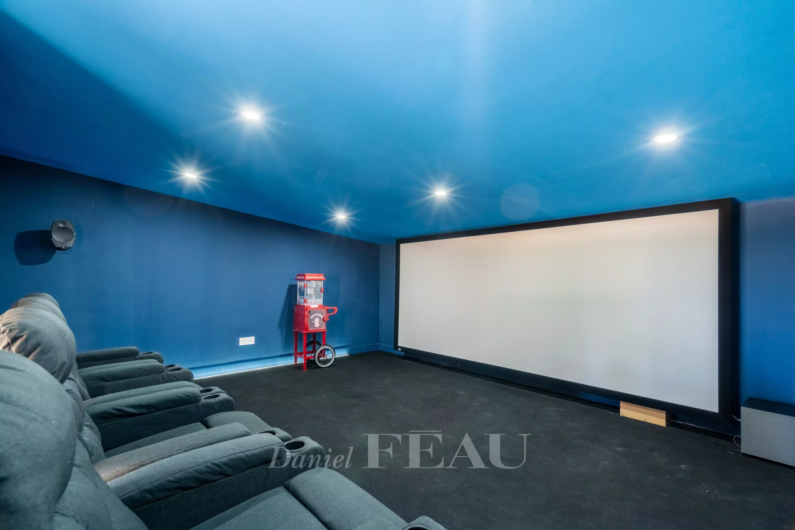 Salle de cinéma privée avec écran et fauteuils confortables.