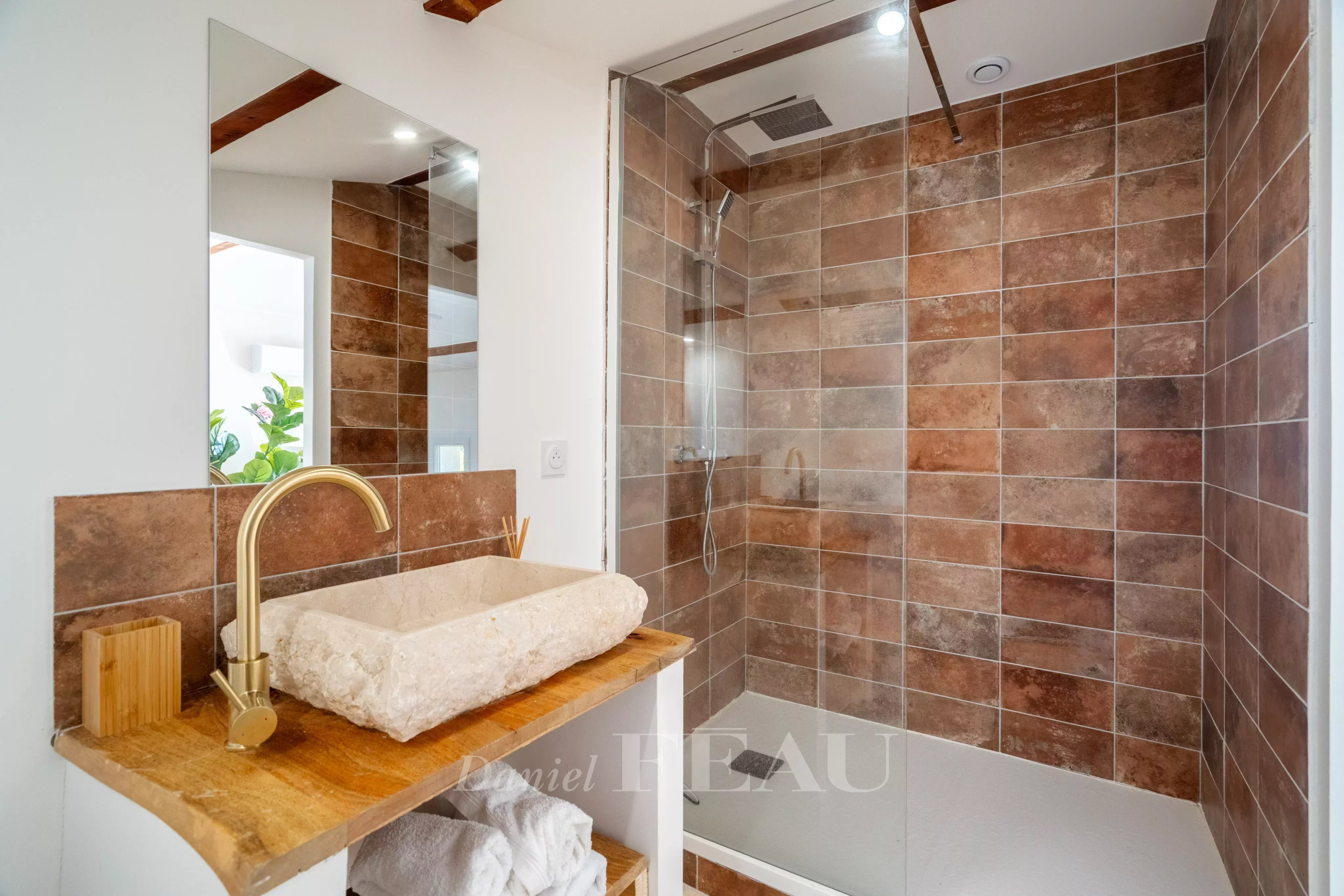 Salle de bain moderne avec douche en verre et lavabo en pierre, décorée de carreaux marron.