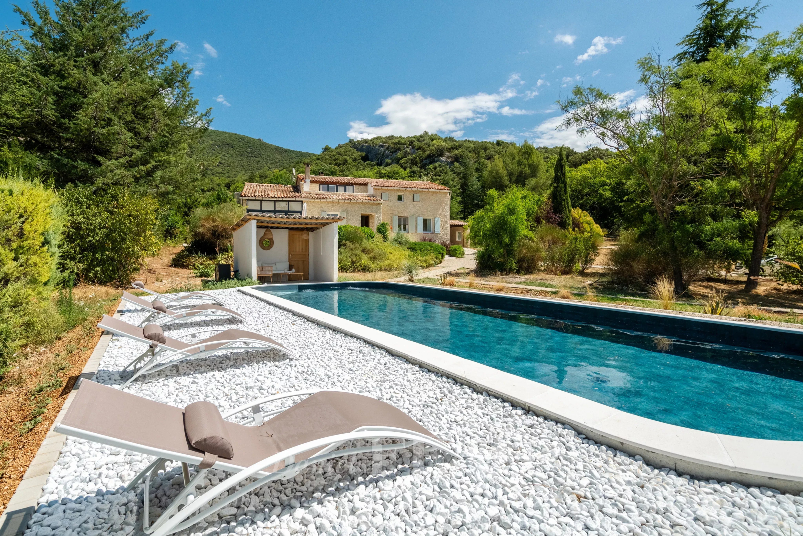 Villa restaurée avec piscine et chaises longues, entourée de verdure à Rustrel.