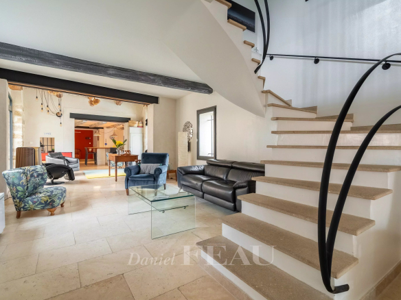 Intérieur d'un mas rénové du XVIIIème siècle à Avignon, avec un salon et un escalier en pierre.
