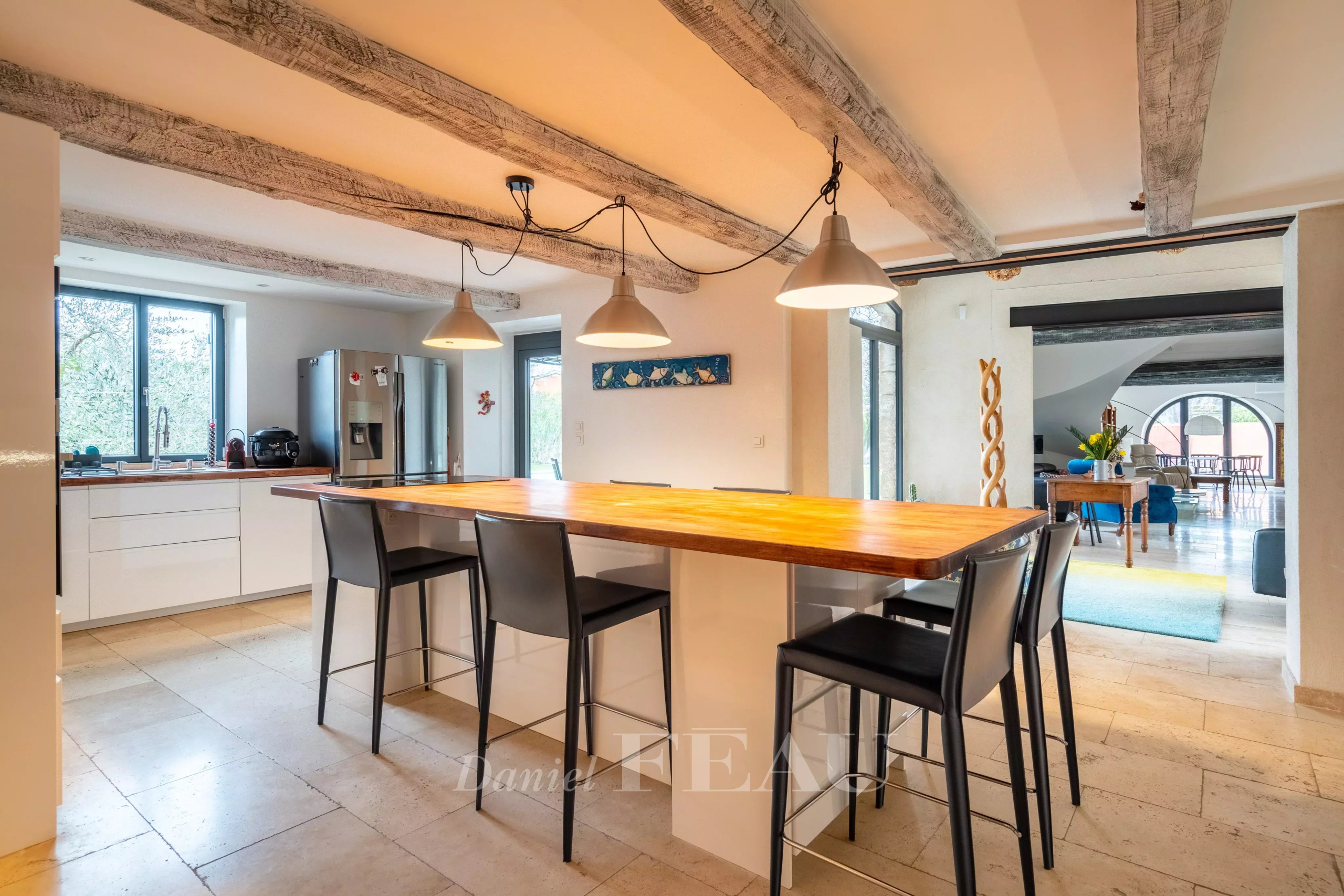 Intérieur d'un mas du XVIIIème siècle rénové, avec une cuisine moderne et un bar en bois.