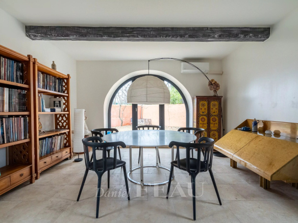 Intérieur d'un mas du XVIIIème siècle rénové, avec une table ronde et des chaises noires.