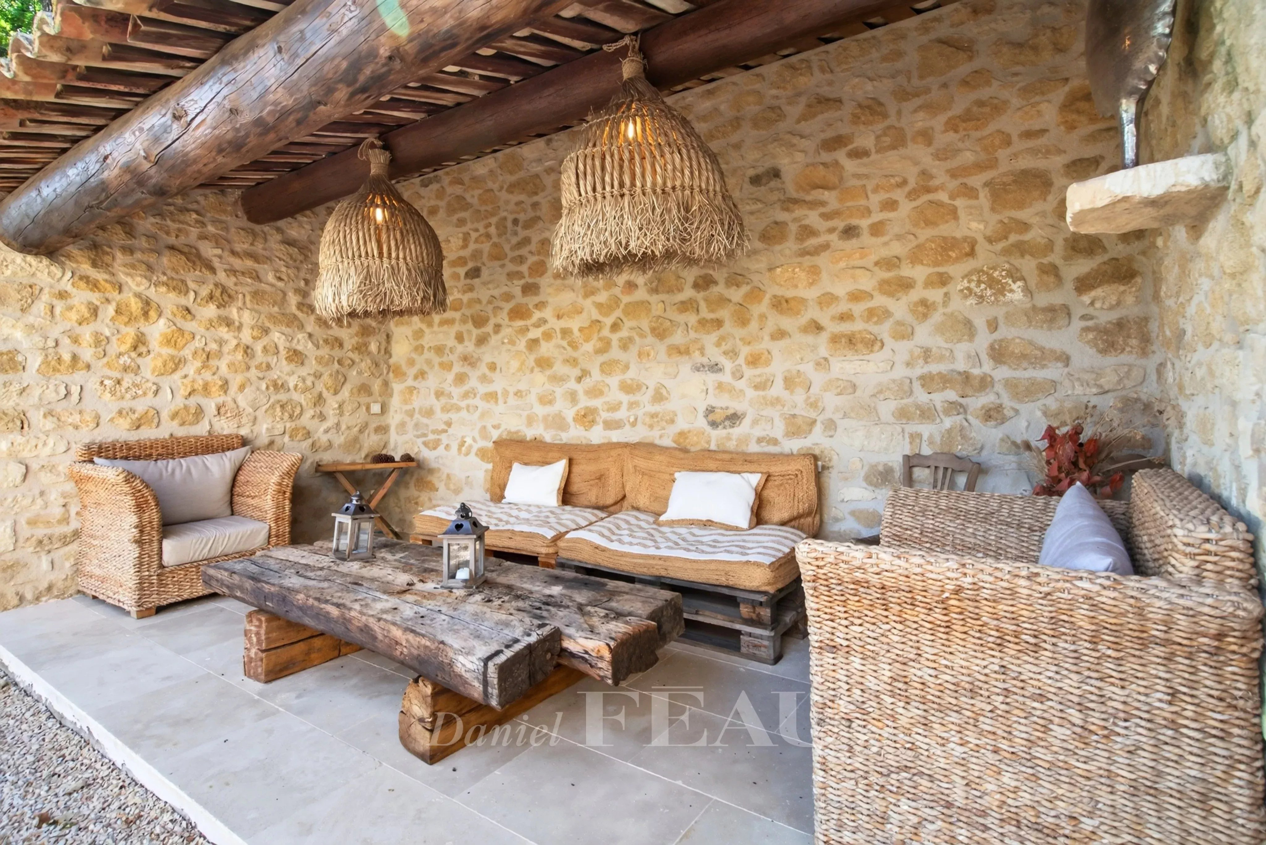 Espace extérieur à Lourmarin Espace extérieur d'une propriété rénovée avec mobilier en rotin et pierres apparentes à Lourmarin.