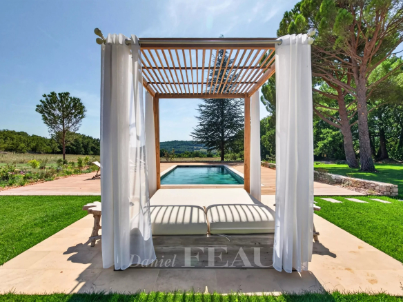 Espace extérieur avec un lit de repos près d'une piscine, entouré de verdure à Lourmarin.