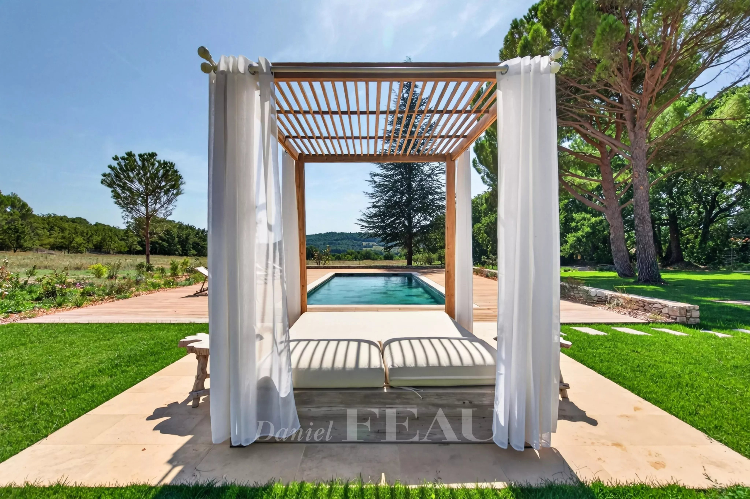 Espace extérieur avec piscine à Lourmarin Espace extérieur avec un lit de repos près d'une piscine, entouré de verdure à Lourmarin.