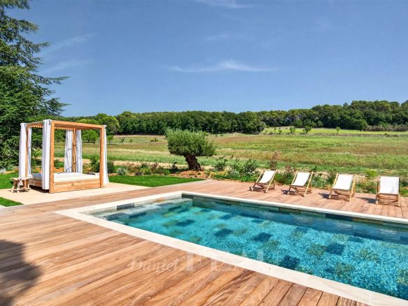 Piscine avec chaises longues et espace détente dans une propriété rénovée à Lourmarin, entourée de nature.