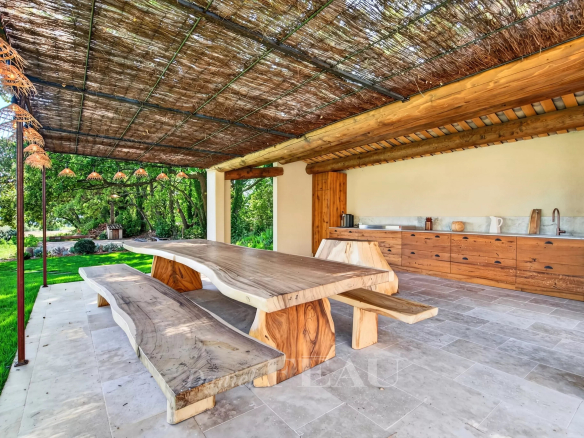 Terrasse extérieure avec table en bois et cuisine d'été dans une propriété rénovée à Lourmarin.