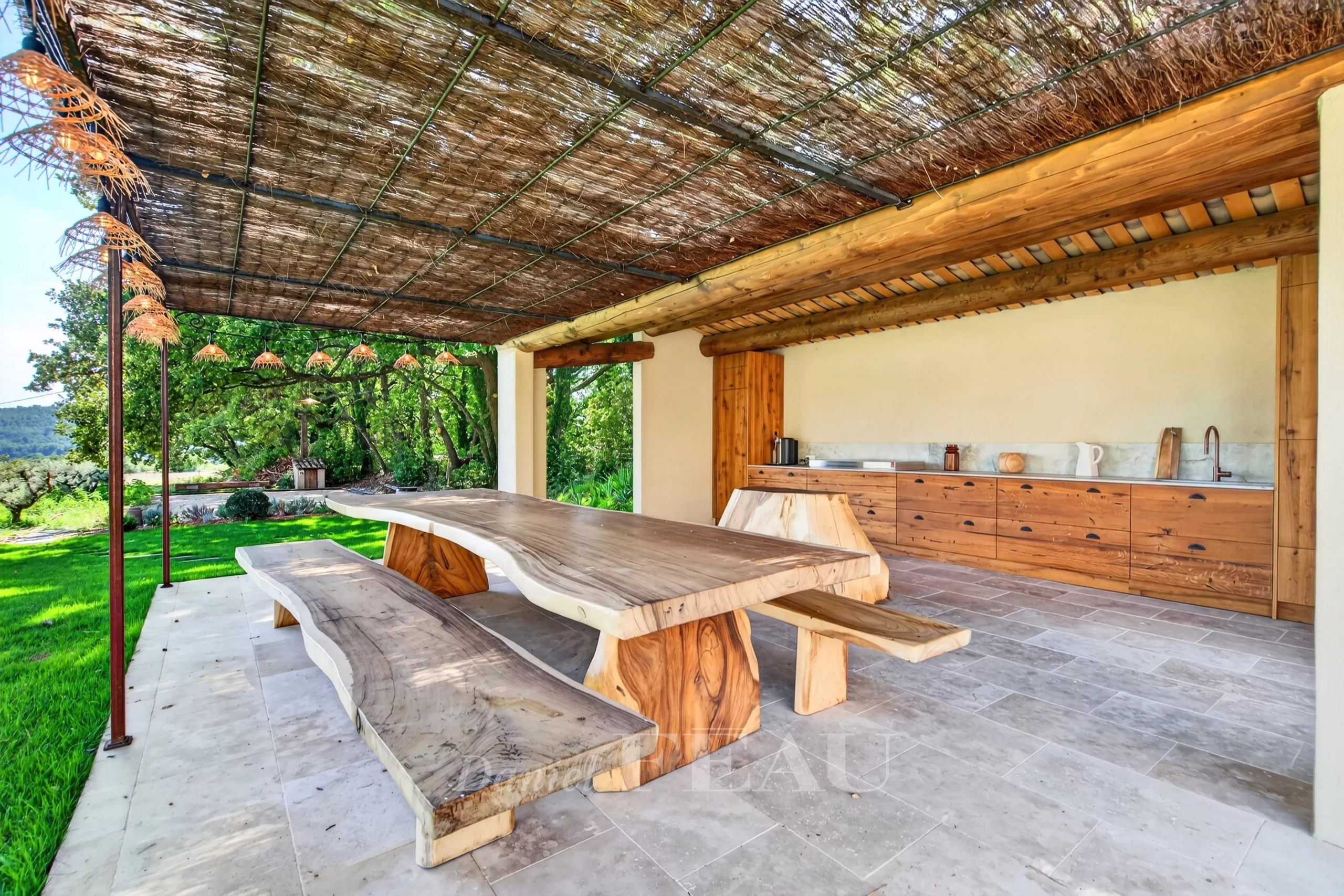 Terrasse de propriété à Lourmarin Terrasse extérieure avec table en bois et cuisine d'été dans une propriété rénovée à Lourmarin.