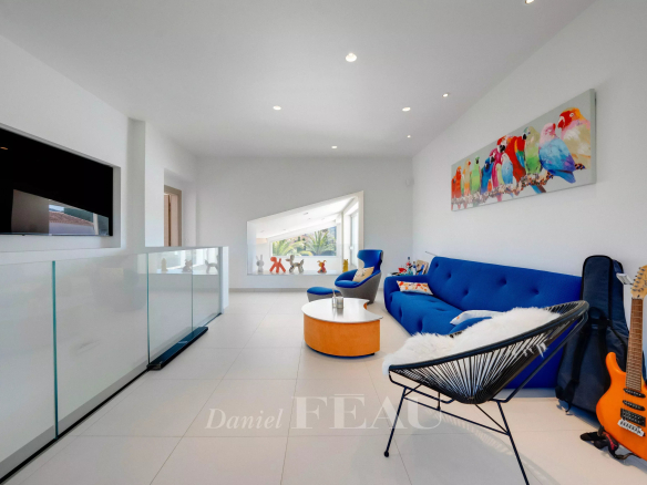 Bright contemporary living room with white walls, a blue sofa, orange round coffee table, and a colorful bird mural on the wall.
