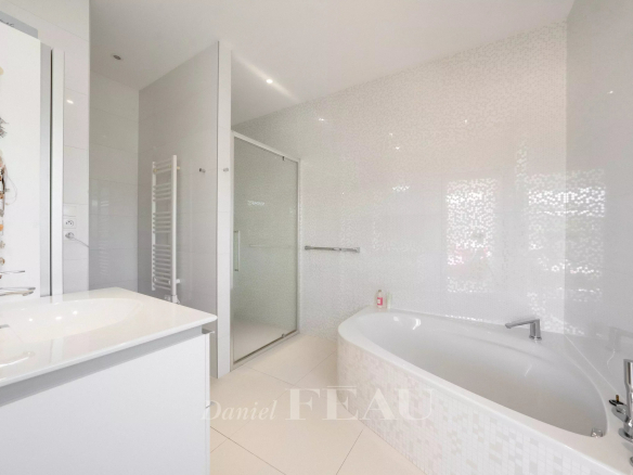 Modern white bathroom with a corner bathtub, glass shower enclosure, and minimalist vanity