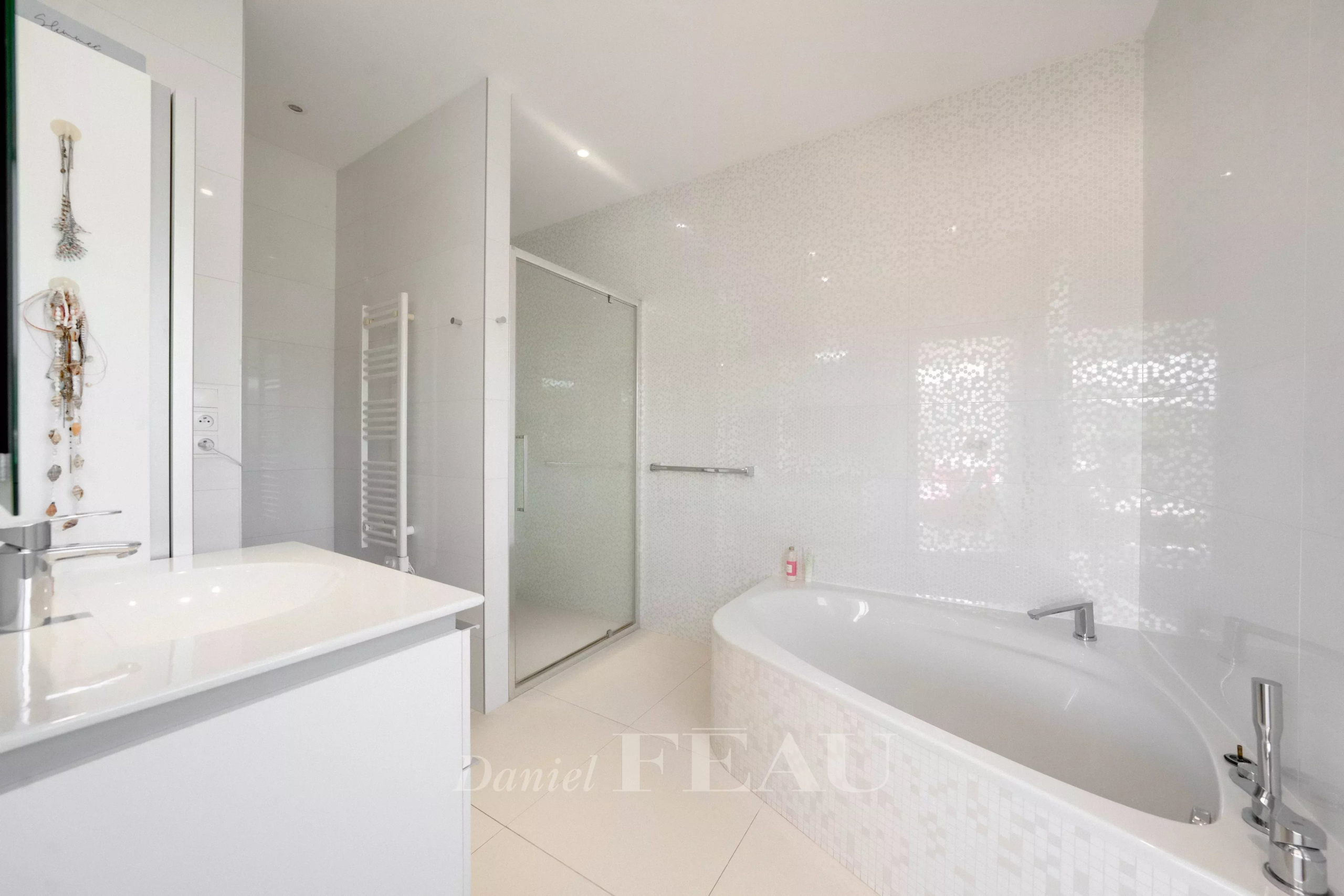 Modern white bathroom with a corner bathtub, glass shower enclosure, and minimalist vanity