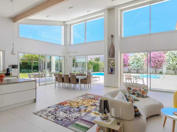 Intérieur d'une villa contemporaine avec un grand séjour lumineux et une vue sur le jardin et la piscine.