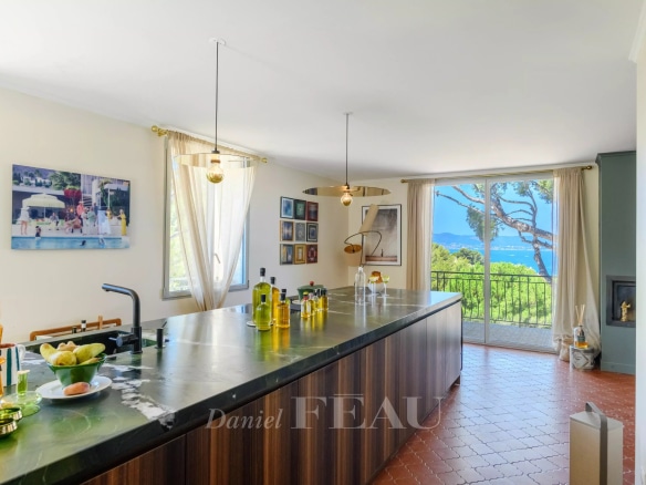 Intérieur d'une maison rénovée avec vue sur la mer, cuisine moderne et baies vitrées.