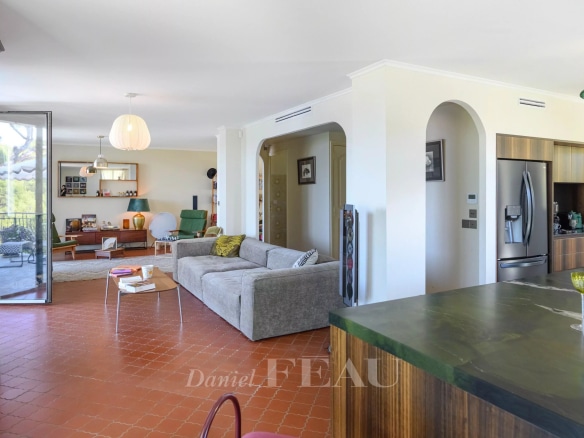 Intérieur d'une maison rénovée avec vue sur la mer, salon spacieux et cuisine moderne.