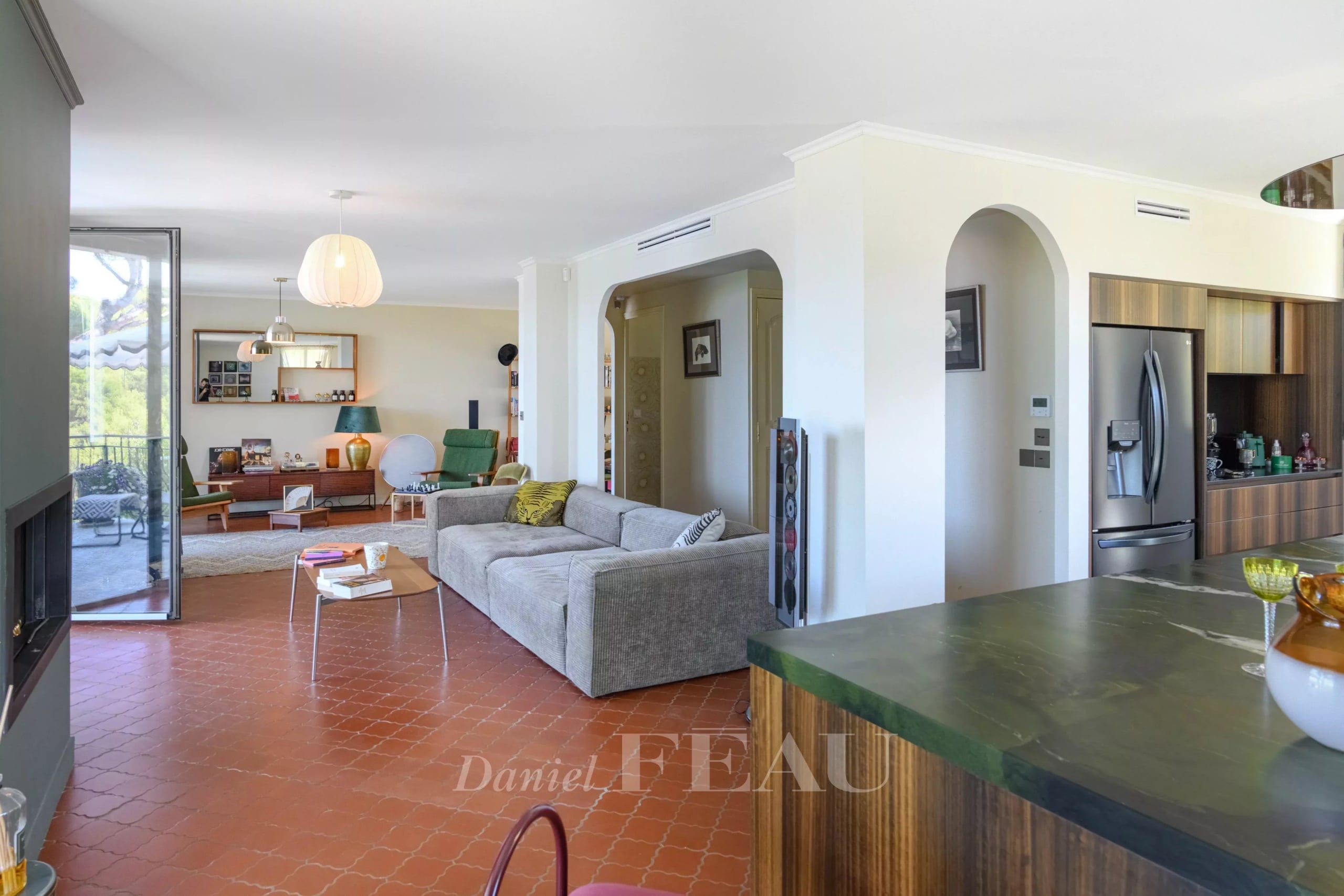 Intérieur d'une maison rénovée avec vue sur la mer, salon spacieux et cuisine moderne.