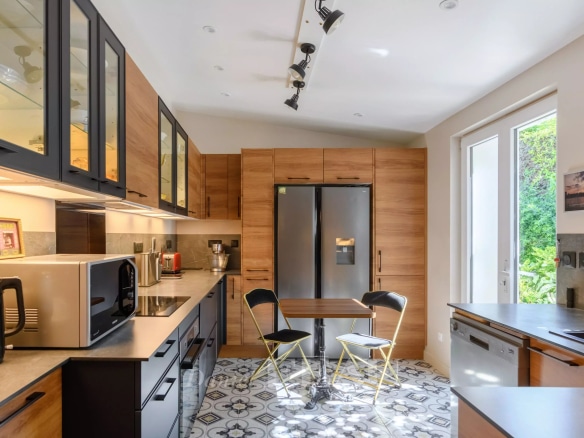 Cuisine moderne avec meubles en bois et carrelage décoratif, lumière naturelle entrant par une fenêtre.