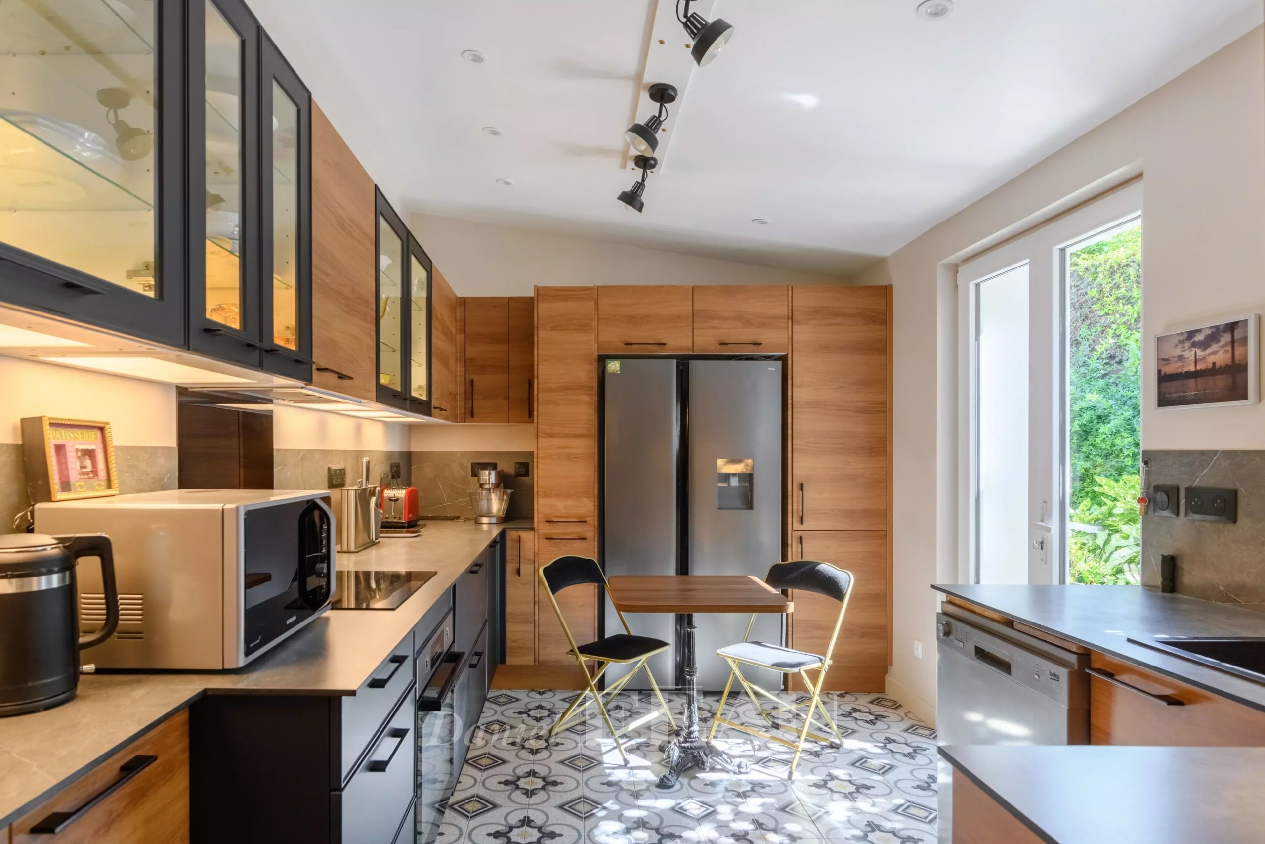 Cuisine moderne avec meubles en bois et carrelage décoratif, lumière naturelle entrant par une fenêtre.