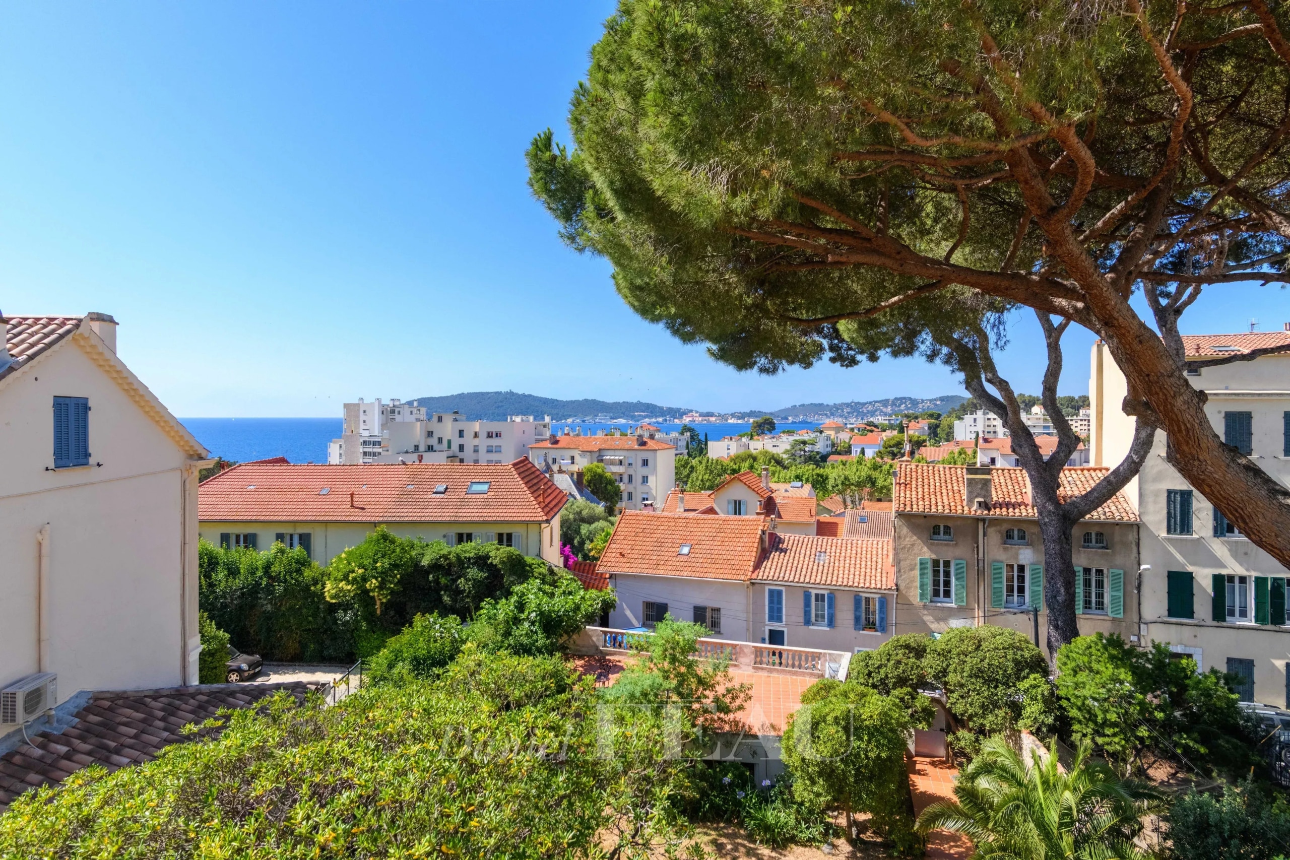 Vue panoramique sur le quartier du Mourillon à Toulon, avec des maisons et la mer en arrière-plan.