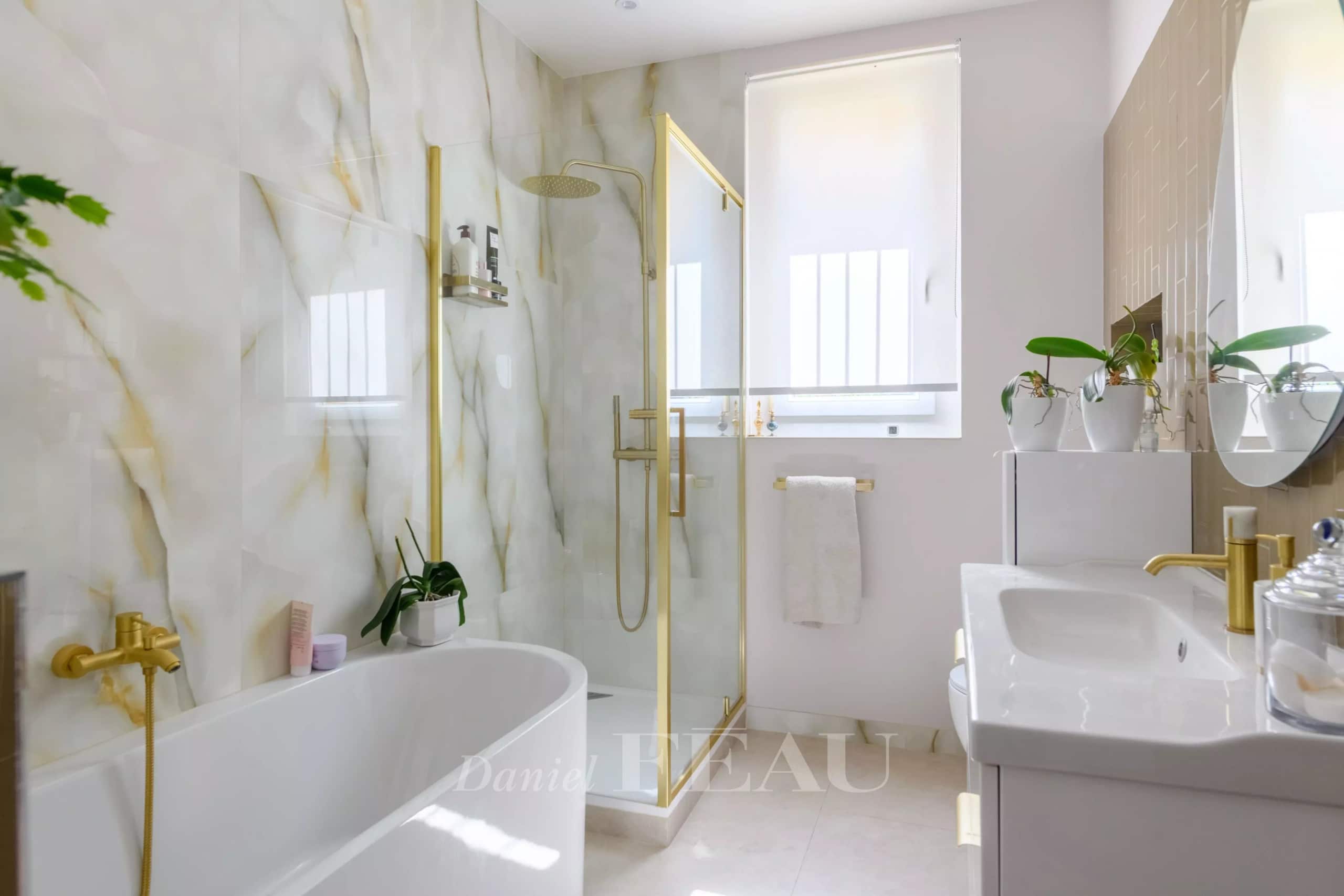 Salle de bain moderne avec baignoire, douche en verre et décor en marbre.