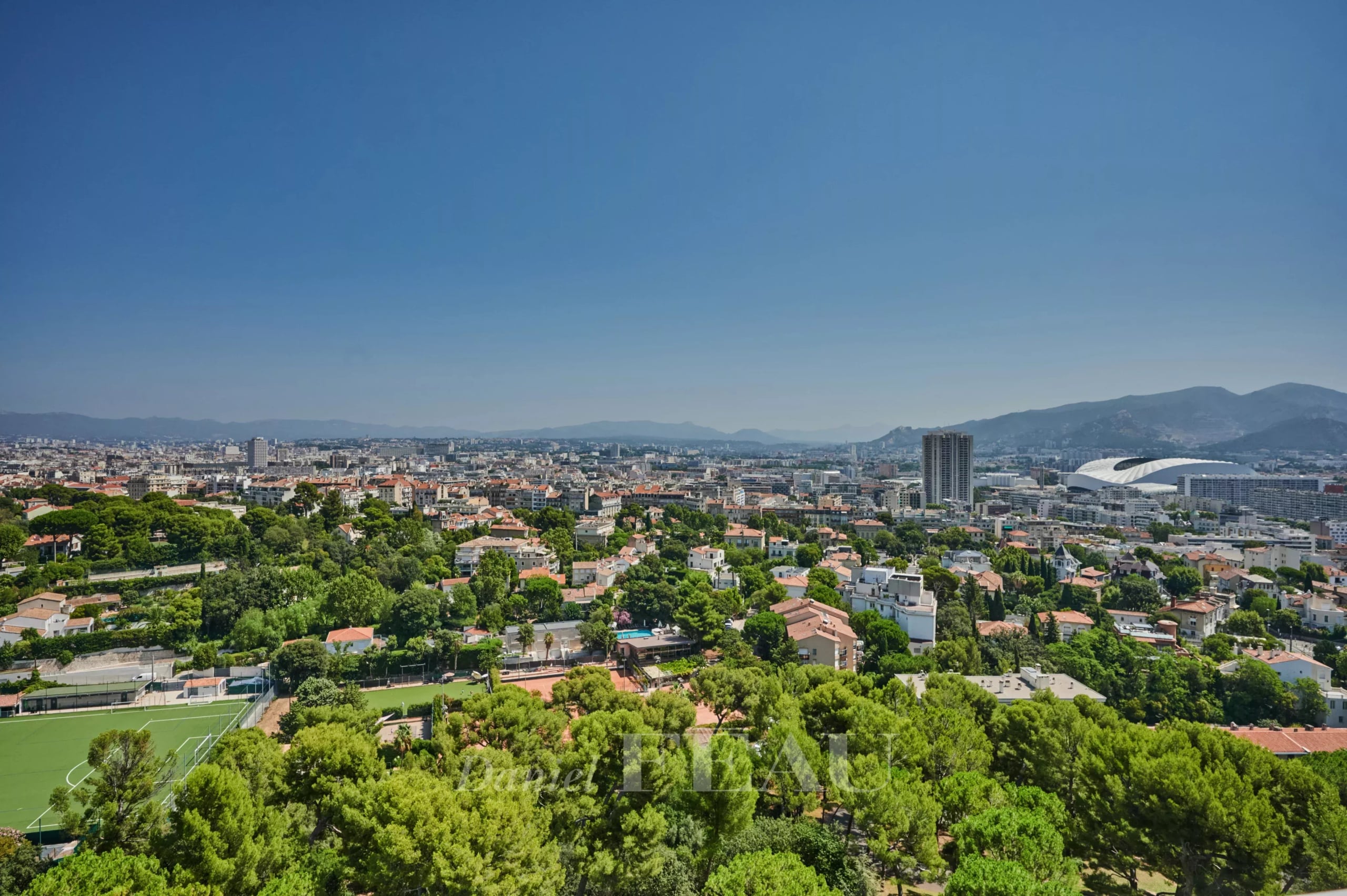Vue panoramique depuis un appartement à Marseille 8ème Vue panoramique sur Marseille depuis un dernier étage, avec des bâtiments et des espaces verts visibles.