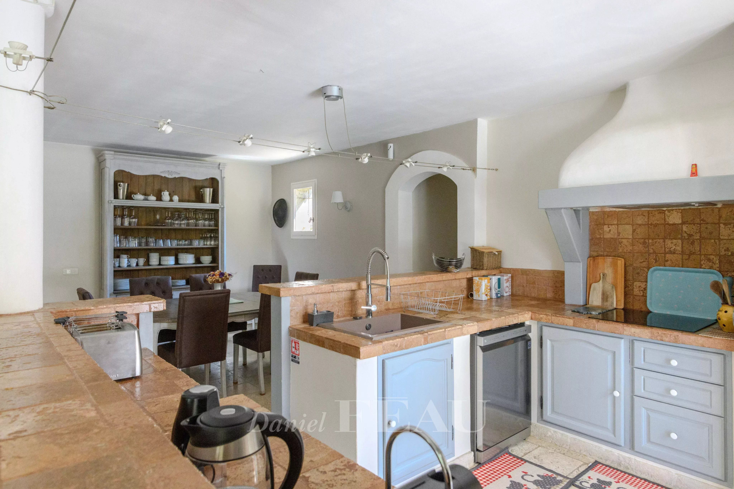 Kitchen of a Provençal house with modern elements, open to a dining room.