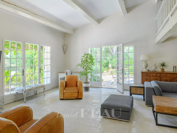 Interior of a house with a bright living room, windows open onto the garden.
