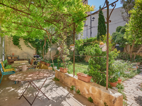 Jardin verdoyant d'une maison à Marseille 7ème avec tables et chaises.