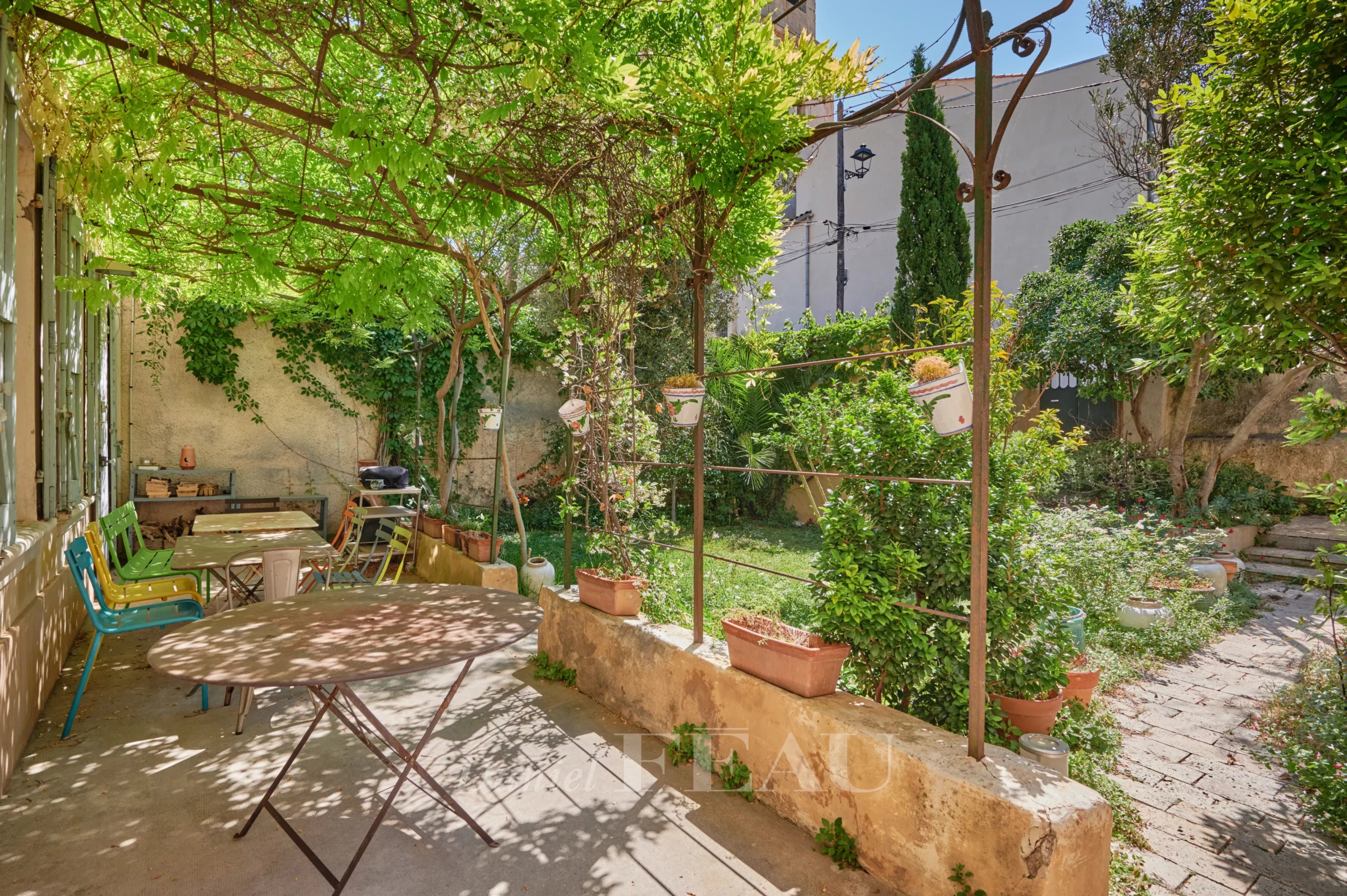 Jardin verdoyant d'une maison à Marseille 7ème avec tables et chaises.