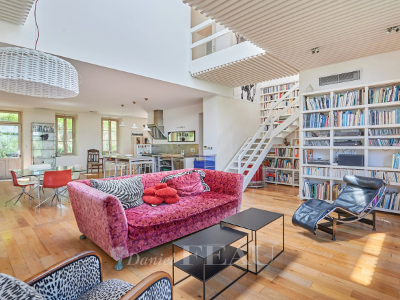 Intérieur d'une maison moderne avec salon lumineux, bibliothèque et cuisine ouverte.