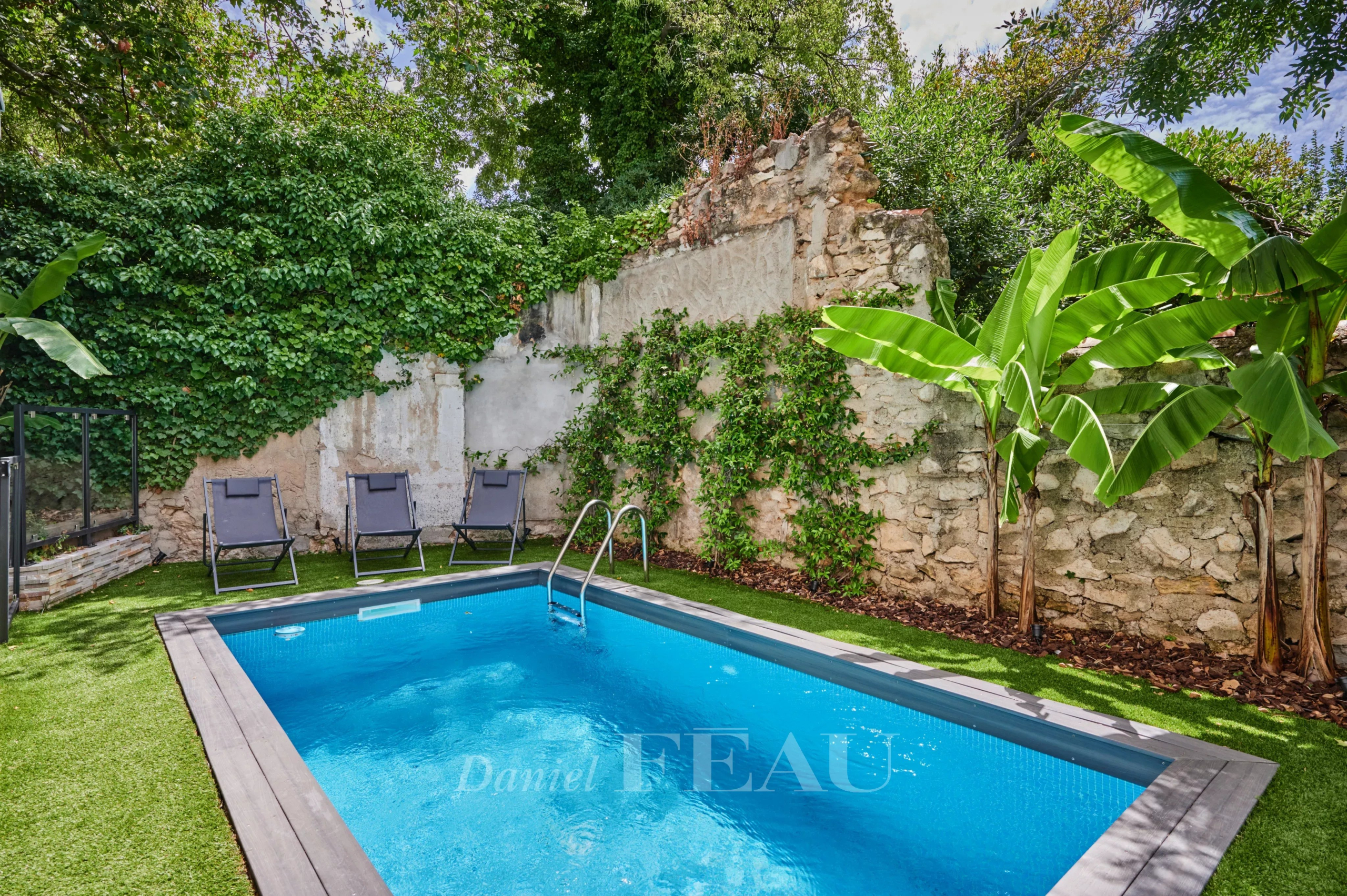 Piscine dans un jardin avec des chaises longues et des plantes tropicales, Marseille 8ème.