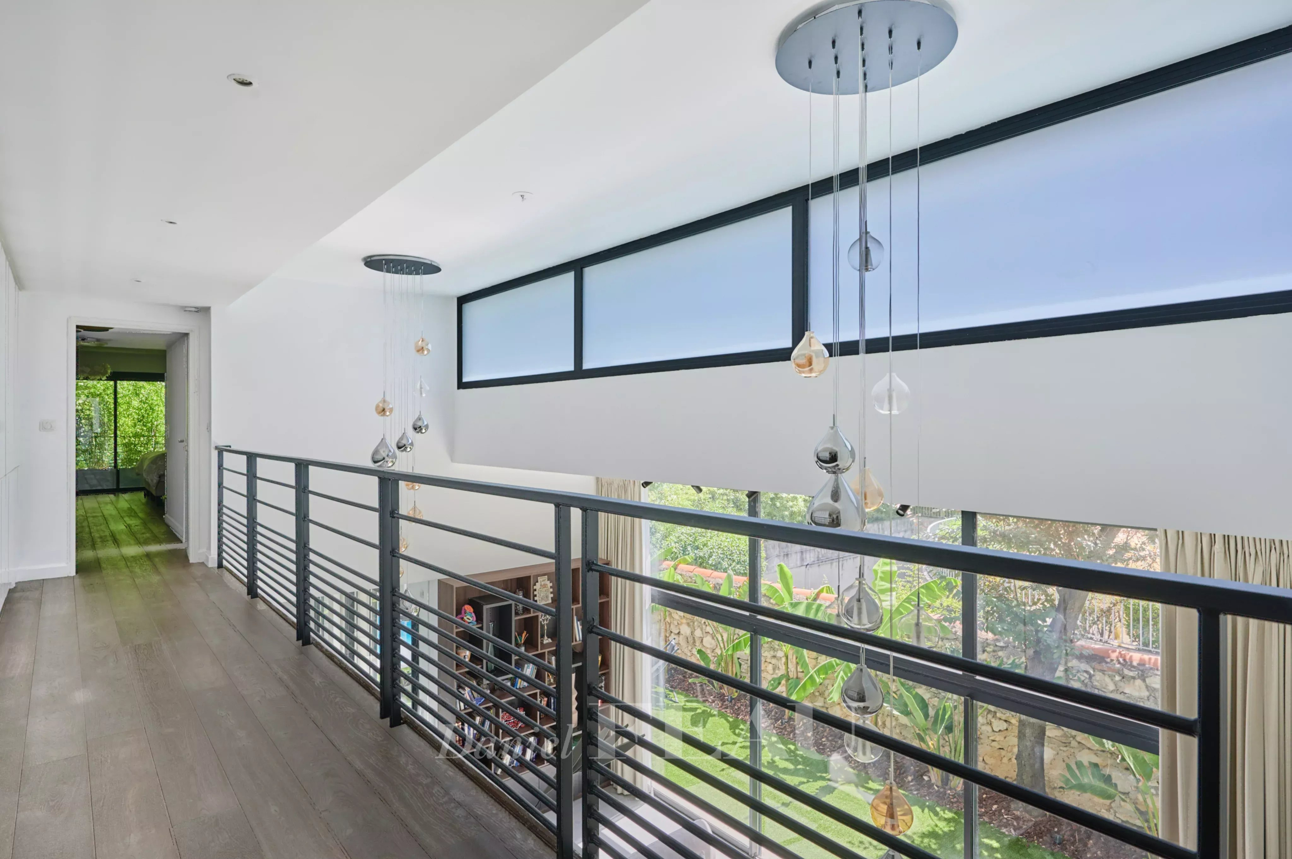 Intérieur d'une maison contemporaine avec balustrade et fenêtres laissant passer la lumière.