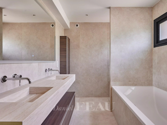 Salle de bain moderne avec baignoire et double vasque en pierre.