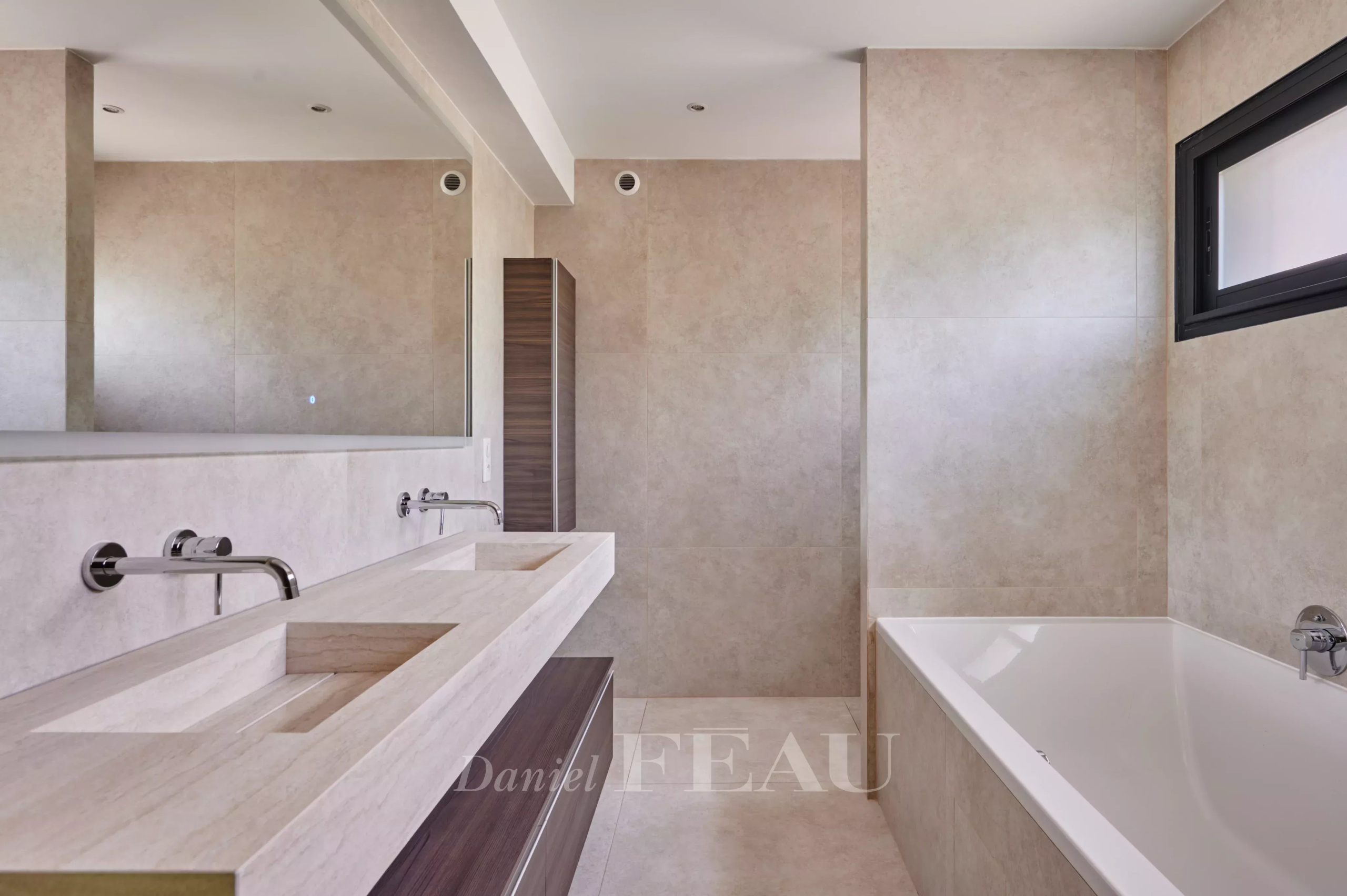 Salle de bain moderne avec baignoire et double vasque en pierre.