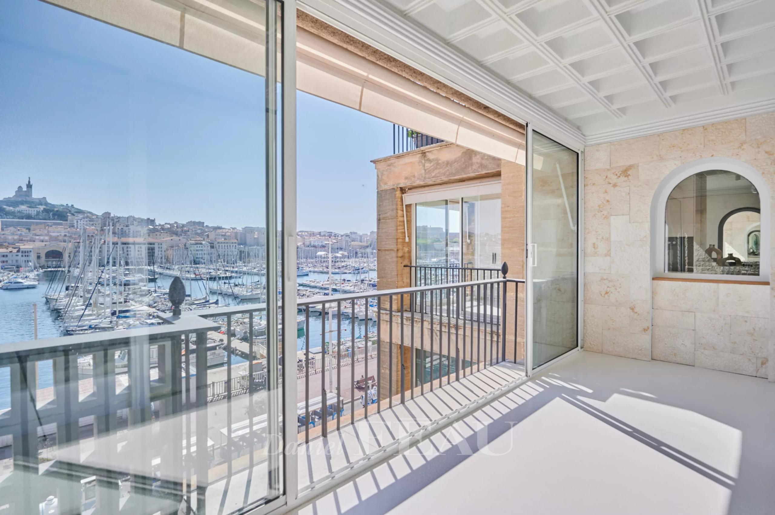 Vue panoramique depuis un appartement rénové à Marseille, montrant le Vieux-Port et la Bonne Mère.