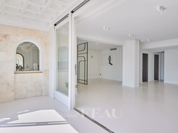Intérieur d'un appartement rénové avec vue sur le Vieux-Port à Marseille, murs clairs et espace lumineux.