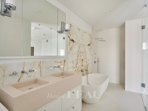 Salle de bain moderne avec baignoire, double vasque et murs en marbre.