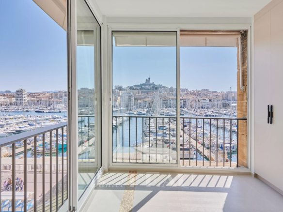 Balcon d'un appartement rénové avec vue sur le Vieux-Port de Marseille et la basilique Notre-Dame de la Garde.