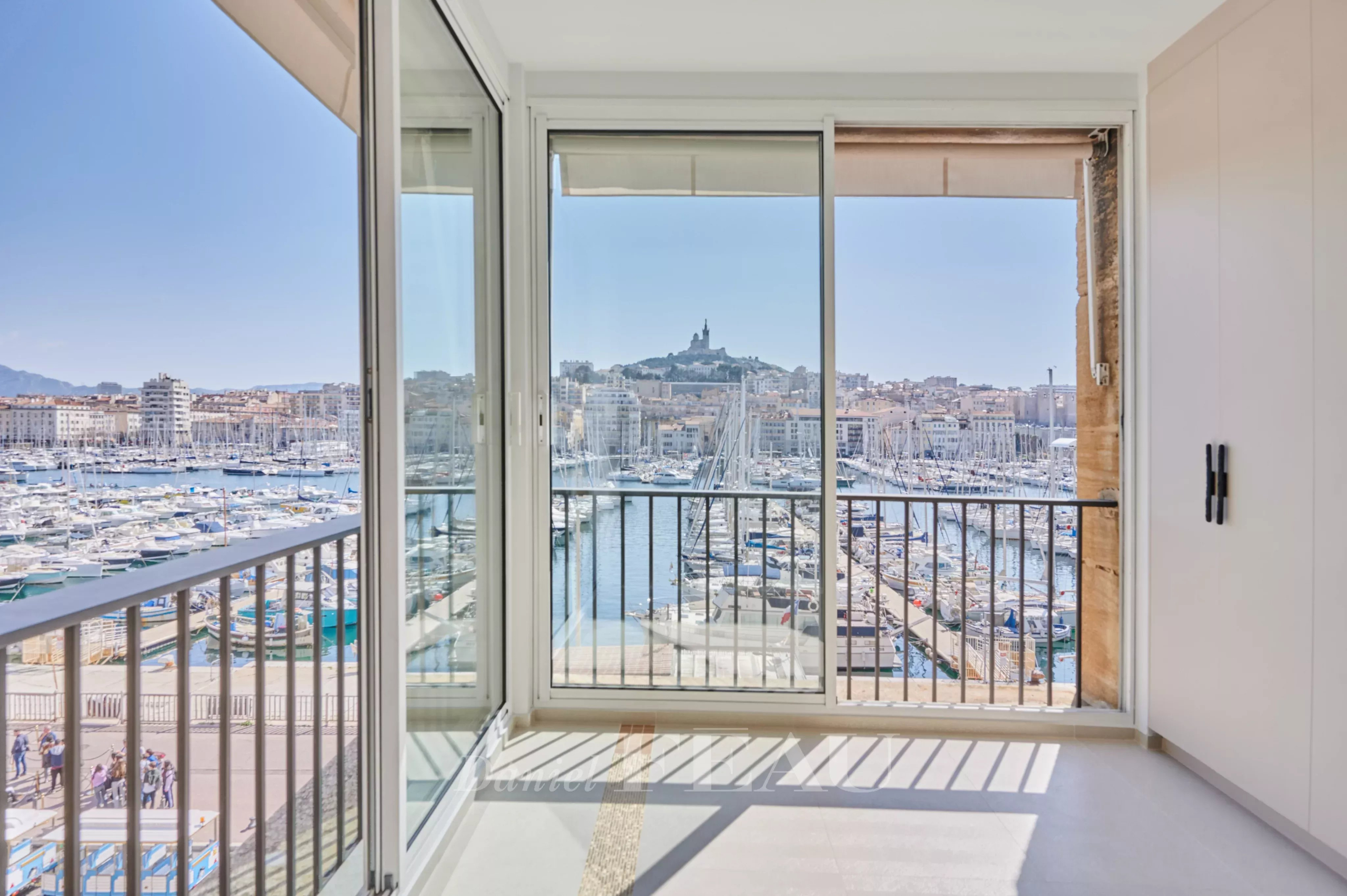 Balcon d'un appartement rénové avec vue sur le Vieux-Port de Marseille et la basilique Notre-Dame de la Garde.