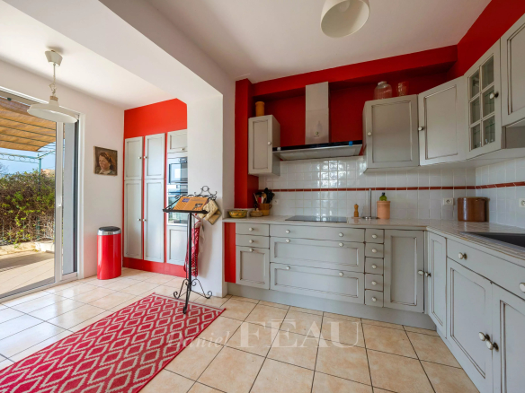 Cuisine moderne avec éléments gris et rouge, accès à une terrasse extérieure.