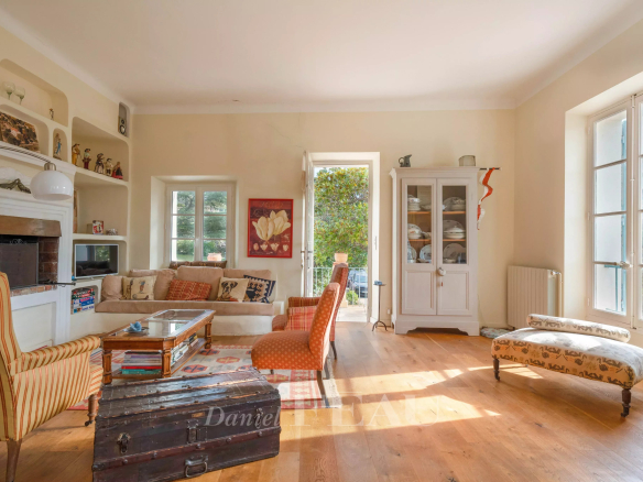 Intérieur d'une maison de caractère avec salon lumineux, mobilier vintage et vue sur la nature.