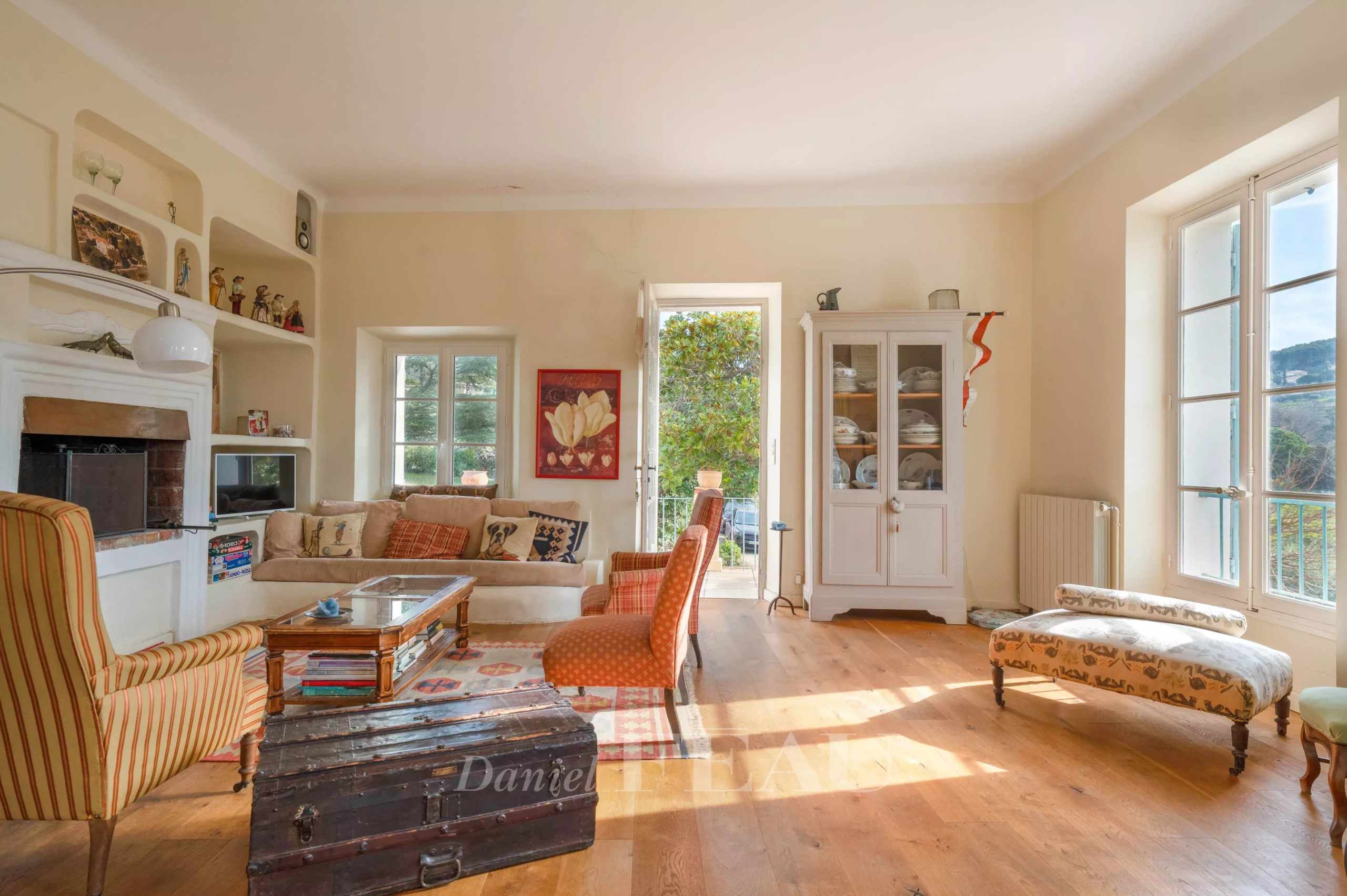 Intérieur d'une maison de caractère avec salon lumineux, mobilier vintage et vue sur la nature.