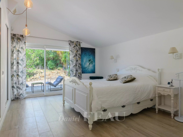 Chambre lumineuse avec lit double et accès à un espace extérieur, décorée de manière contemporaine.
