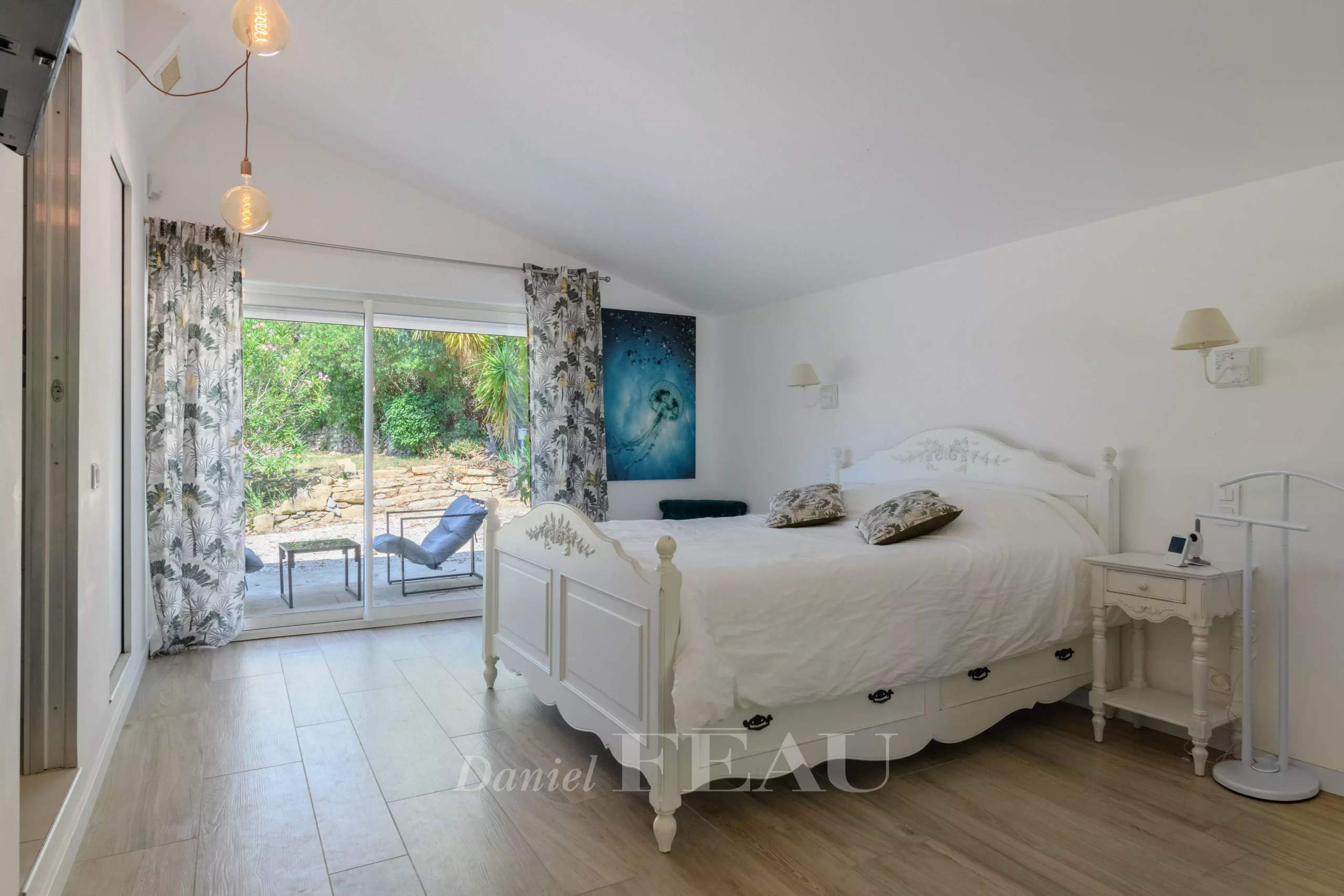 Chambre lumineuse avec lit double et accès à un espace extérieur, décorée de manière contemporaine.