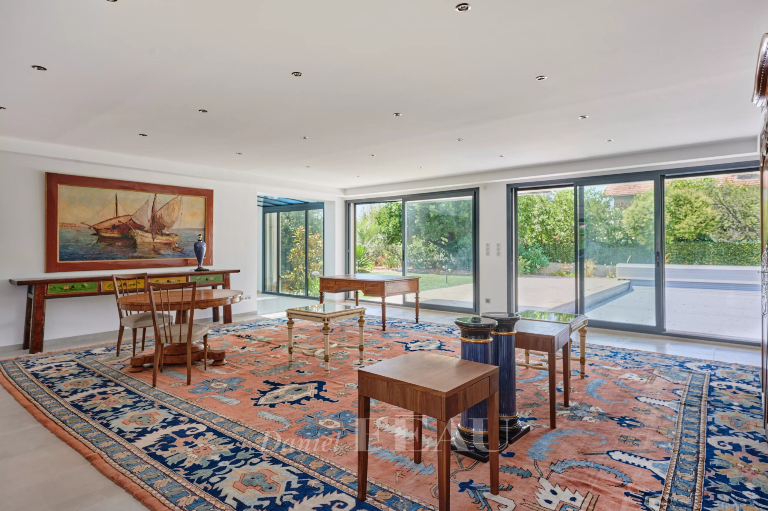Intérieur d’une maison familiale à Marseille 8ème Intérieur d'une maison spacieuse avec un grand salon, des fenêtres donnant sur le jardin et un tapis coloré.