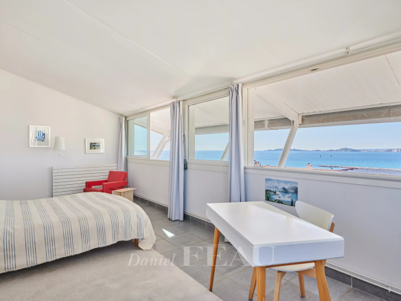 Chambre lumineuse avec vue sur la mer à Marseille, fenêtres ouvertes.
