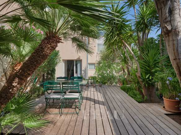 Terrasse en bois avec mobilier de jardin entourée de palmiers.
